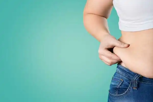 Image of woman pinching her love handles to show weight gain Bridgwater
