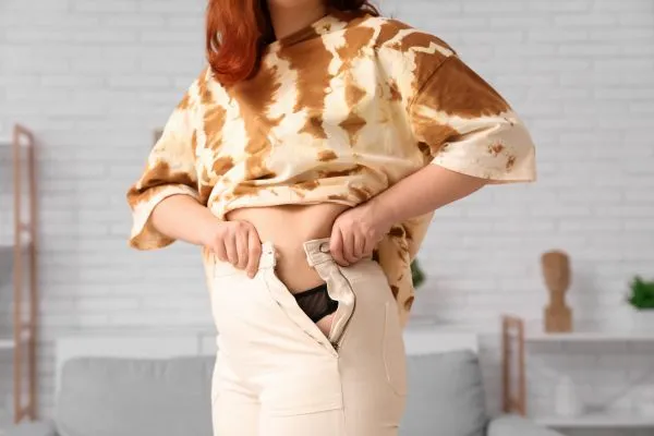 Image of woman trying to do her trousers up after pregnancy weight gain Bridgwater