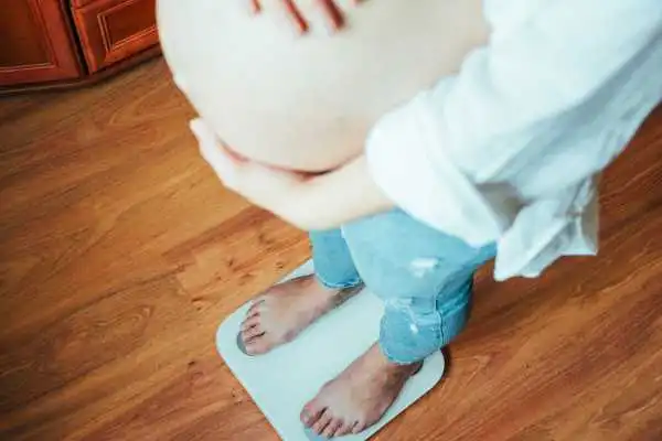 Image of woman weighing herself and experiencing weight gain through pregnancy Bridgwater
